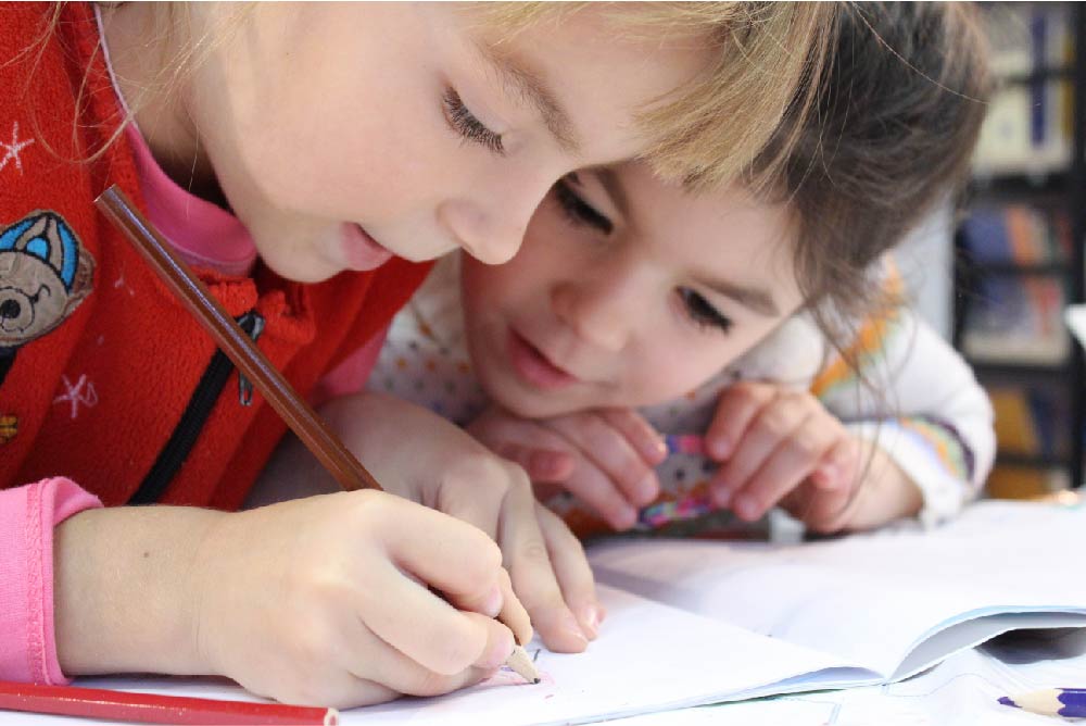 Two girls on desk looking at a notebook